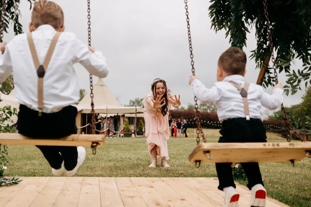 children playing on swings at a rustic wedding in the uk